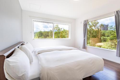 two beds in a white room with a window at WaPura Rusutsu in Rusutsu