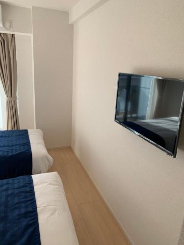Habitación de hotel con TV de pantalla plana en la pared en Hotel Emir, en Tokio