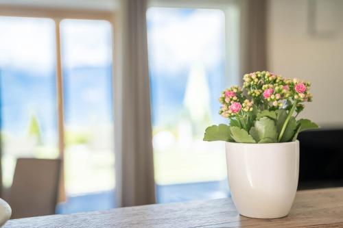 a white vase with flowers sitting on a table at Gasserhof - Chalet A in Frassinetto