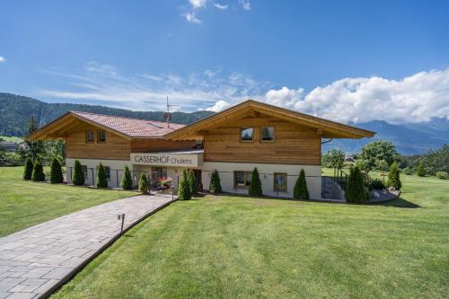 a large wooden house with a grass yard at Gasserhof - Chalet A in Frassinetto