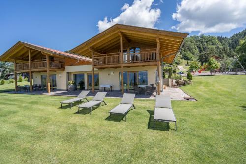 a group of chairs sitting on the grass in front of a house at Gasserhof - Chalet A in Frassinetto