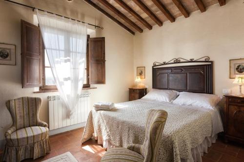 um quarto com uma cama, uma cadeira e uma janela em Agriturismo MONSOLE - Montalcino em Montalcino