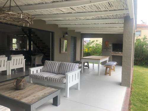 a patio with a couch and a table and chairs at Pringle @ 865 Jally in Pringle Bay