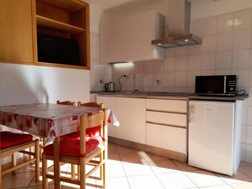 a kitchen with a table and a refrigerator at Accogliente struttura nel cuore della Valmalenco in Chiesa in Valmalenco