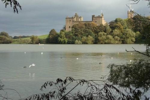 a castle sitting on top of a lake with birds at Sunny House with views to Edinburgh Skyline in Edinburgh