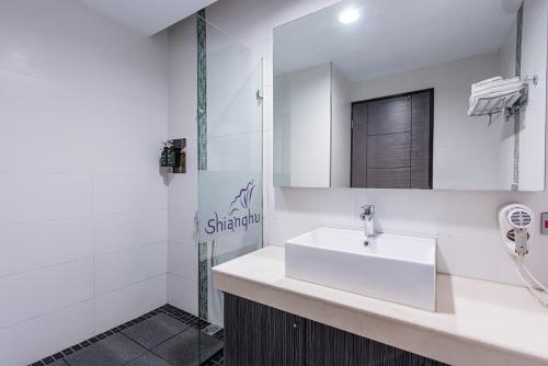 a white bathroom with a sink and a mirror at Shianghu Boutique Hotel in Chiayi City