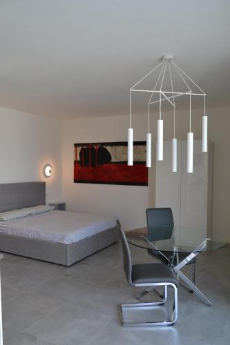 a bedroom with a bed and a glass table and a chair at aura AR holiday-home in Peschiera del Garda