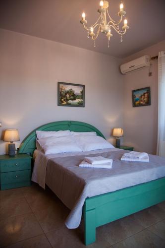 a bedroom with a green bed and a chandelier at Villa Mary in Kefallonia