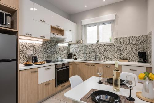 a kitchen with white cabinets and a table with wine glasses at JT Apartments in Kissamos