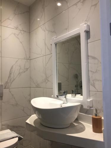 ein Badezimmer mit einem weißen Waschbecken und einem Spiegel in der Unterkunft City Pearl Hotel in Hersonissos