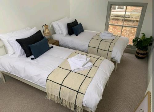 a room with three beds and a window at Ferry Lane Cottage in King's Lynn