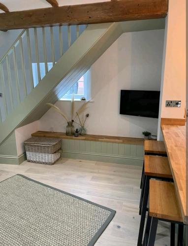 a living room with a staircase with a flat screen tv at Ferry Lane Cottage in King's Lynn