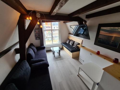 a living room with a couch and a tv at Appartement Havenzicht, gelegen aan zee met zeezicht in Vlissingen