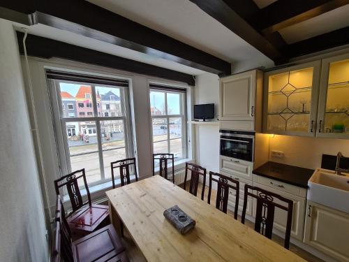 a kitchen with a wooden table and chairs and a kitchen with a window at Appartement Havenzicht, gelegen aan zee met zeezicht in Vlissingen