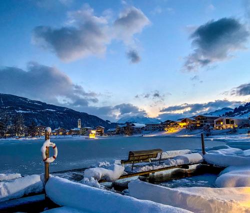 a winter view of a lake with snow on the ground at Mira Piz Signina - Wunderbare Dachwohnung mit Blick in die Berge in Laax