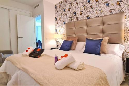 - une chambre avec un grand lit blanc et des oreillers bleus dans l'établissement LUJOSO APARTAMENTO NUEVO PLAYA CENTRO, à Estepona