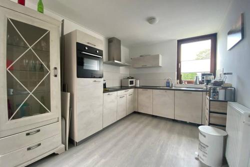 a large kitchen with white cabinets and a window at Traumhaftes geräumiges Ferienhaus in Meernähe in Bruinisse