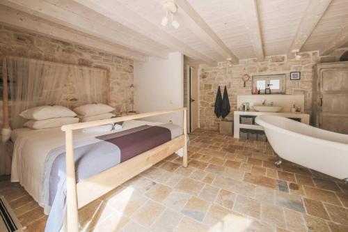 a bedroom with a bed and a tub and a sink at Paxos StoneHouse in Gaios