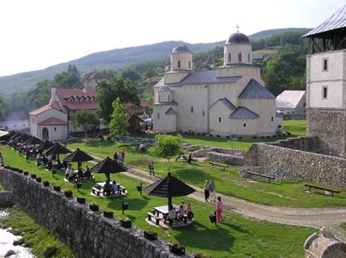 a group of people sitting around tables in front of a castle at Vila ZLATARSKA PAHULJA in Nova Varoš