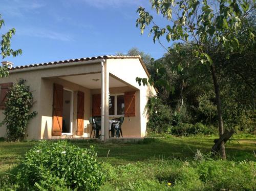 a small white house with a table in the yard at Residence Cucunacciu in Cargèse