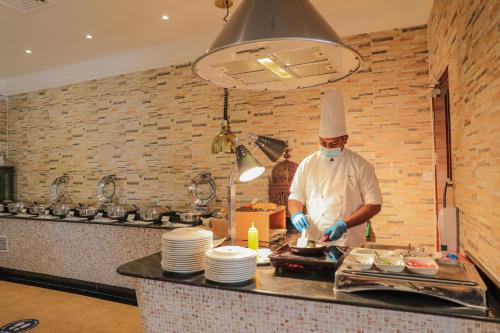 a chef standing in a kitchen preparing food at Dhafra Beach Hotel in Jebel Dhanna