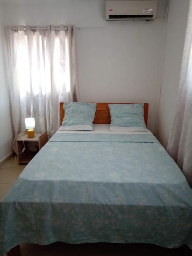 a bedroom with a bed with a blue comforter at Le Mastro Chambre d'hôtes in Mamoudzou