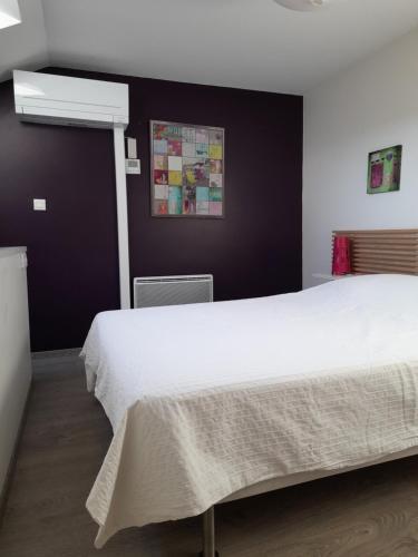 a bedroom with a white bed and a black wall at L' Atelier de la Monnaie in Crémieu