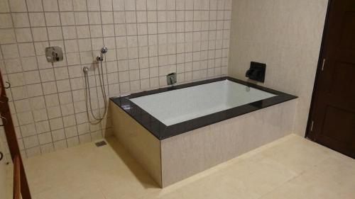 een badkamer met een bad en een tegelwand bij K RESORT in Pondicherry
