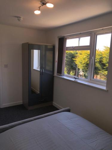 a bedroom with a bed and two windows at Driftwood Apartment - Skegness in Skegness