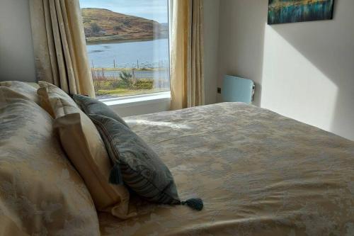a bed with pillows in a bedroom with a window at The Causeway in Bracadale