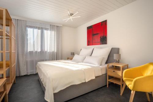 ein weißes Schlafzimmer mit einem großen Bett und einem gelben Stuhl in der Unterkunft Ferienhaus Villa Milla Nürnberg in Nürnberg