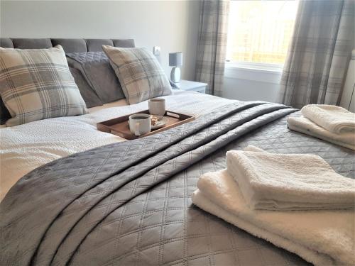 a bed with two towels and a tray on it at Hunters Holiday Cottage in Saint Boswells