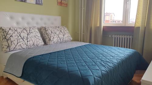 a bedroom with a bed with a blue comforter and a window at Apartman Sweet dreams 1 in Niš