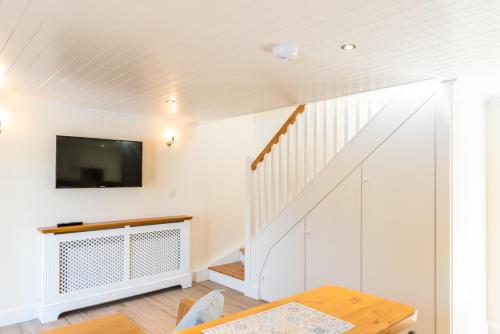 a living room with a staircase and a flat screen tv at Ardnavaha House - Poolside Cottages in Clonakilty