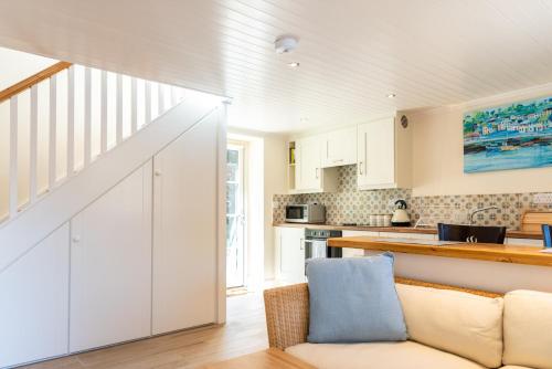 a kitchen with white cabinets and a couch at Ardnavaha House - Poolside Cottages in Clonakilty