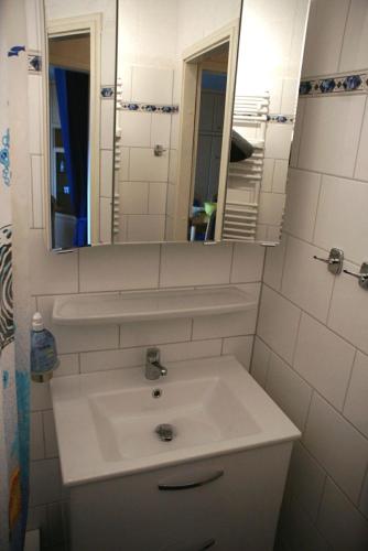 a white bathroom with a sink and a mirror at Ferienwohnung Himmelblau - Altenau Harz in Altenau
