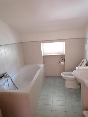 a white bathroom with a tub and a toilet at L'Uliveto in Montebuono