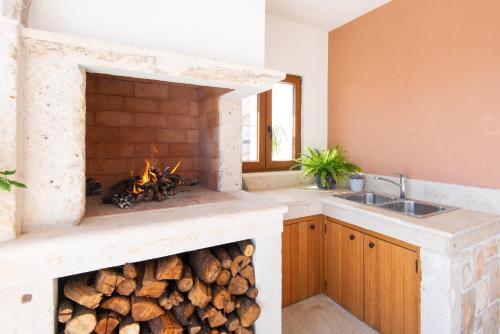 cocina con chimenea llena de troncos en Villa Aria, en Orebić