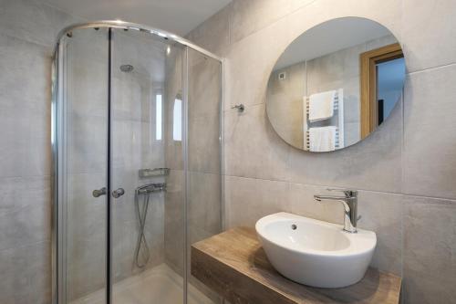 a bathroom with a sink and a shower with a mirror at Margo Beach Hotel in Gythio