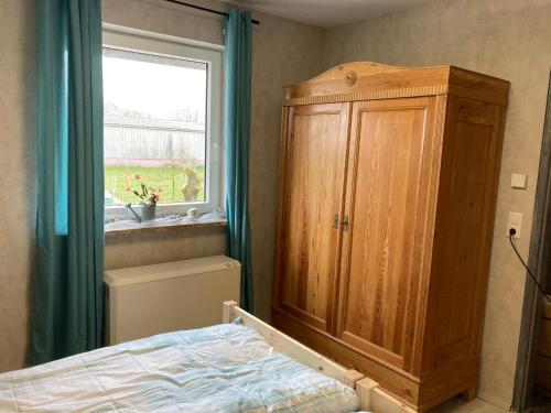 a bedroom with a wooden cabinet and a bed and a window at Haus Wald und Wiese Wohnung Wald in Ehndorf