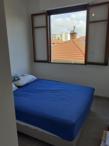 a bedroom with a blue bed and a window at La verdure au cœur de Nice in Nice