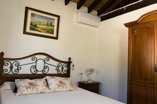 1 dormitorio con 1 cama con cabecero de madera en Malaga mountains winehouse with private pool, en Borge