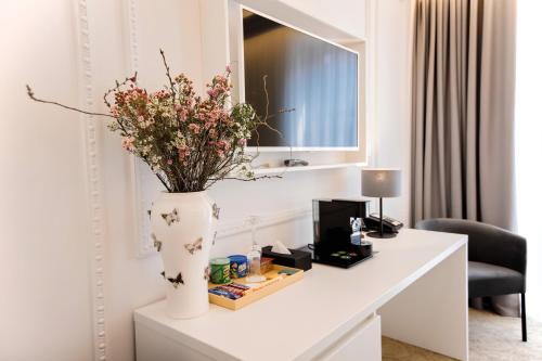 a white table with a vase with flowers on it at Bon Hotel in Dnipro