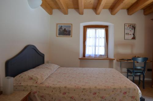 a bedroom with a bed and a window and a chair at B&B Arlanch 8 in Vallarsa