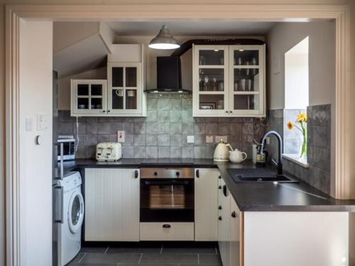 a kitchen with white cabinets and a sink and a dishwasher at Rosies in Clifden