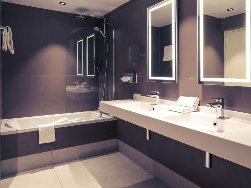a bathroom with two sinks and a tub and mirrors at Hotel Mercure Blois Centre in Blois