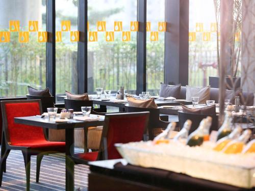 a dining room with tables and chairs and windows at Novotel Kolkata Hotel and Residences in Kolkata