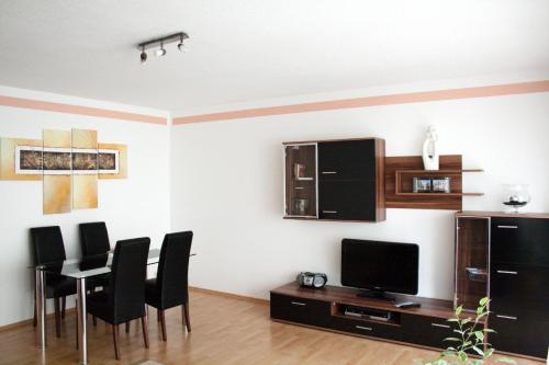 sala de estar con mesa, sillas y TV en Appartement Julija, en Baden-Baden