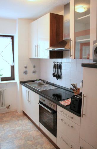 a kitchen with white cabinets and a stove top oven at Appartement Julija in Baden-Baden