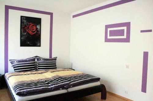 バーデン・バーデンにあるアパートメント ユリアの紫と白の壁のベッドルーム1室、ベッド1台が備わります。